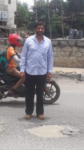 Syed Shahi next to a filled pothole